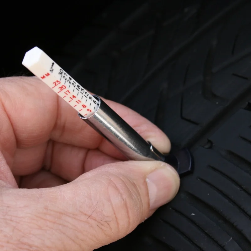 lastik diş derinliği ölçümü yapan bir profesyoneli gösteren bir görsel